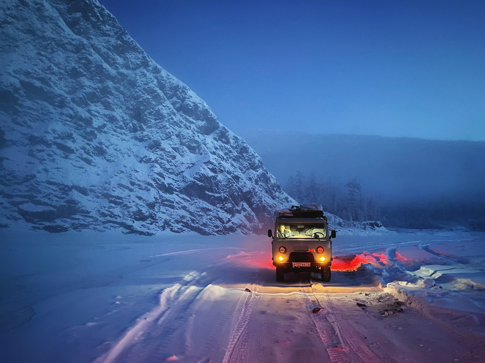 在雪道的汽车在多雪的山旁边。